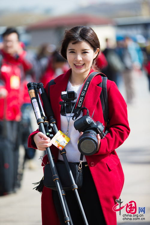 2016年兩會(huì)，人民大會(huì)大堂前，一位笑容燦爛的紅衣女記者正步入大會(huì)堂。中國(guó)網(wǎng) 鄭亮 攝