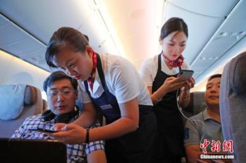 資料圖：乘務(wù)員們在客艙內(nèi)為旅客調(diào)試機(jī)上上網(wǎng)功能。<a target='_blank' ><p  align=